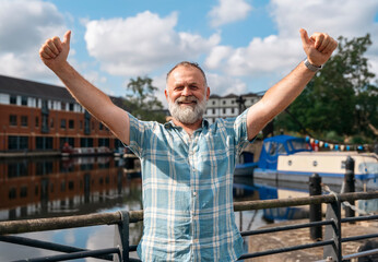 a mature bearded man sitting  on a bench, walking at a quay, enjoing warm days of the spring, summer