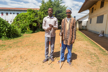 Blind friends stand still then continue for a walk while helping themselves with their white canes