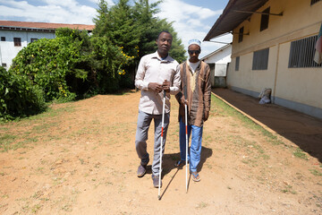 Two blind friends help each other with their white canes by walking toward the promenade.