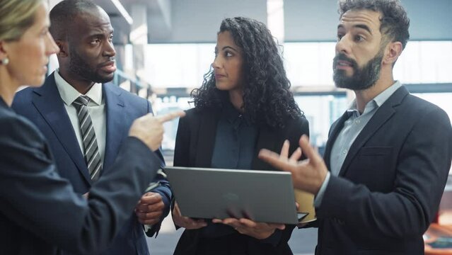Modern Multi-Ethnic Office Meeting: Ambitious Motivated Businesswoman Presenting Investment Strategy to Partners, Pitching. Diverse Team of Businesspeople Talk in Hallway Using Laptop Computer