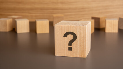 wooden cube with question mark on wooden background. Space for text