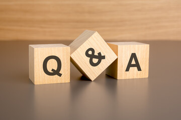 Q and A letters on wooden cubes against brown background with copy space. concept of sale and...