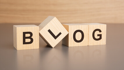 four wooden cubes with the letters BLOG on the bright surface of a brown table, business concept