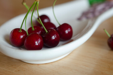 red cherries in white bowl on wooden table close up