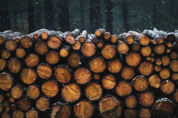 Firewood, log pieces stored under snow in winter. Snowflakes in the air. Holiday atmosphere