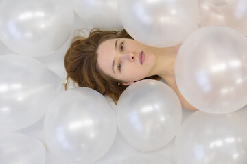 fashion beauty vogue portrait of young sensual redhead woman between white iridescent balloons