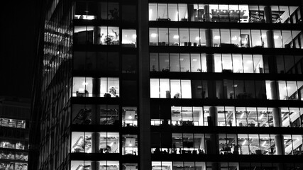 Pattern of office buildings windows illuminated at night. Glass architecture ,corporate building at night - business concept. Black and white.