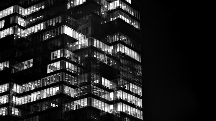 Obraz premium Pattern of office buildings windows illuminated at night. Glass architecture ,corporate building at night - business concept. Black and white.