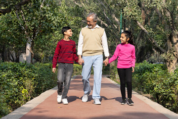 Happy grandfather walking with grand children at park