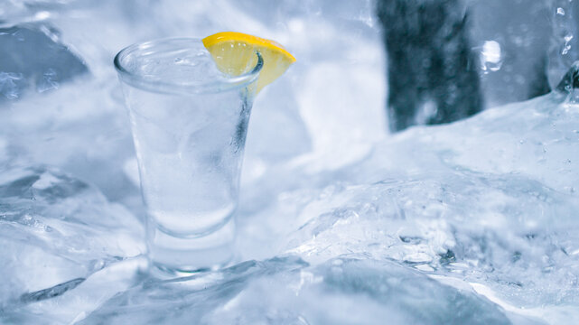 A glass of vodka with ice and lemon
