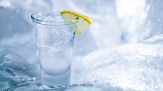 A glass of vodka with ice and lemon