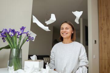 Seasonal allergy free. Happy young woman throws tissues up at home. Healthy life without of runny...