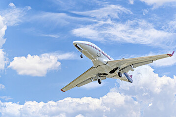 Fototapeta na wymiar Private business plane flying under a blue sky with white clouds