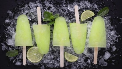 Homemade popsicles with lime juice and mint, mojito fruit ice on a black wooden table. High quality 4k footage
