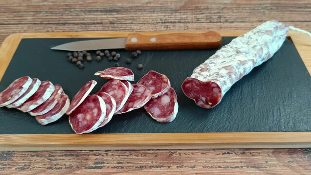 saucisson sec tranch&eacute; sur une planche &agrave; d&eacute;couper	