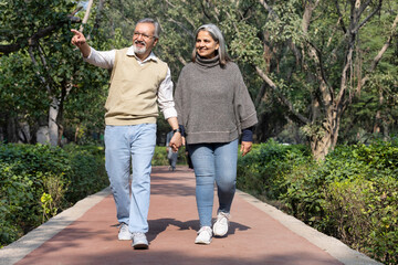 Obraz premium Smiling senior couple enjoying view of nature at public park