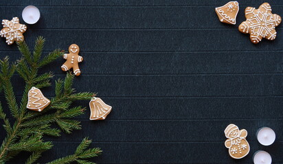 Fototapeta na wymiar Top view of gingerbread and fir branches on a dark craft paper background, creating a New Year's themed ambiance
