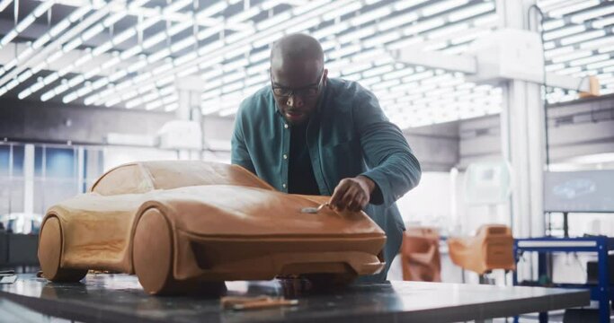 Diverse African Automotive Artist Making Final Strokes on His Latest Concept Car Creation. Black Designer Working on a New Prototype, Sculpting Industrial Plasticine Clay 3D Model of a Sporty Coupe.