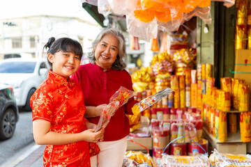 Chinese lunar new year festival and tradition holiday celebration concept. Asian grandmother and grandchild girl buying home decorative ornaments for celebrating Chinese New Year at Chinatown market. - obrazy, fototapety, plakaty