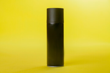 Black spray can isolated on yellow background. Mockup. Can concept. Beauty product concept. Space...