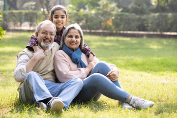 Fototapeta premium Portrait of happy granddaughter embracing loving grandparents