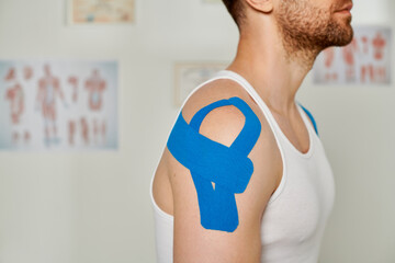 cropped view of man with kinesiological tapes on his shoulder during appointment, healthcare
