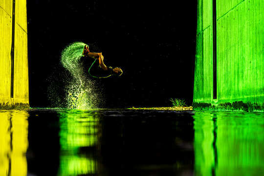 Young man backflipping with water under bridge at night
