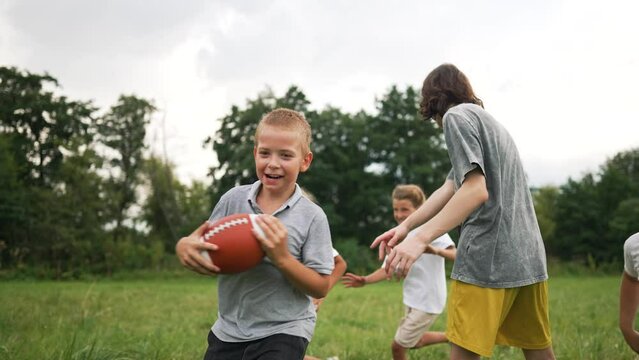 Happy family concept.children playing rugby together in park outdoors.group of children run on green grass and play American football. family playing rugby in a forest park outdoors. children's dream