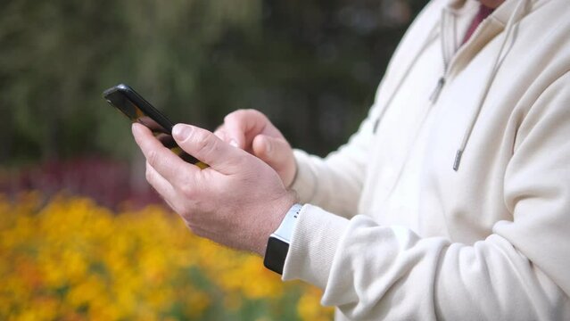 Young male hands touch the phone. Man in a white sweater with a smartphone. Tapping, scrolling, watching video, content, blogs. Modern lifestyle
