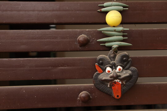 An Indian Black evil eye nazar battu mask with nimbu mirchi or lemon and chilly sign attached by string on iron gate, landscape