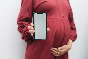 Muslim pregnant woman holding her belly stomach and smartphone