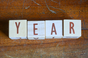 Photo of words with wooden block objects arranged into the word "YEAR" in English