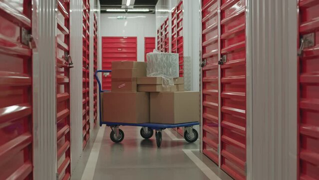 No people shot of dolly cart loaded with cardboard boxes in corridor of self service storage
