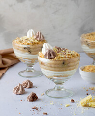 Desserts in glasses. Trifle, layered cheesecake in a glass, decorated with cookies, chocolate and meringue..