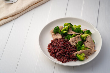 Cooked riceberry rice and Stir fried broccoli with pork tenderloin fillet in white plate.Thai Healthy food for low fat diet menu.