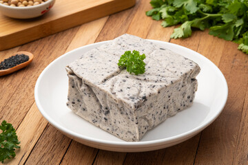 Tofu mix black sesame seeds in white plate on wooden table