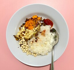 Indonesian style lunch menu. Warm white rice, telor ceplok or sunny side up egg with sambal bawang chili, peanut snack. Low budget but delicious meal isolated on pink background. Makanan rumahan.