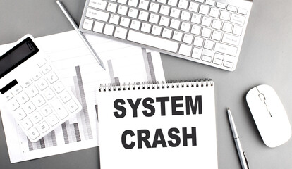 SYSTEM CRASH text written on notebook on grey background with chart and keyboard, business concept