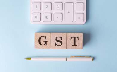 GST on wooden cubes with pen and calculator, financial concept