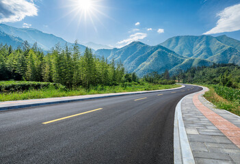 Country road and green bamboo forest with mountain natural landscape on a sunny day