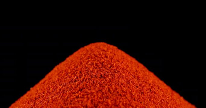 Heap of ground chili pepper or smoked paprika. Sprinkle smoked paprika powder, black background