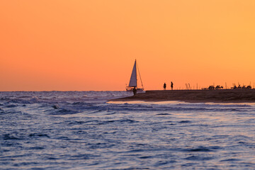 Beautiful bright orange sunset and a sailboat sailing on the ocean near the Canary Island of...