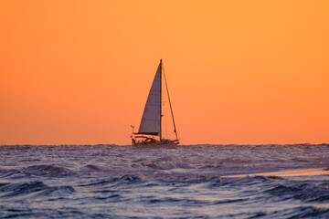 Beautiful bright orange sunset and a sailboat sailing on the ocean near the Canary Island of...