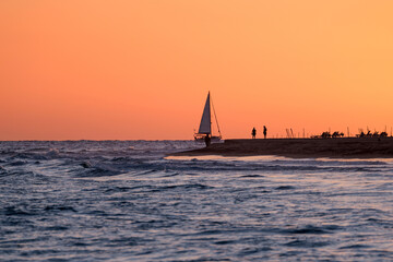 Beautiful bright orange sunset and a sailboat sailing on the ocean near the Canary Island of Fuerteventura, Spain.