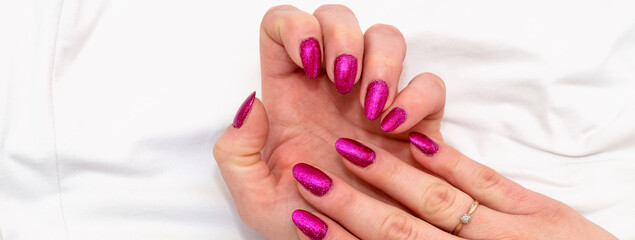 Close-up of well-groomed female pink nails. Beautiful clear fingers of a young girl with nice manicure and Glitter Nail Polish. Girl hands on a white background. Banner..