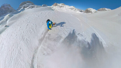 SELFIE: Spraying powder snow while extreme snowboarder descends snowy mountain