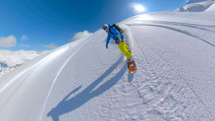 SELFIE, LENS FLARE Cheerful snowboarder rides untouched powder snow on sunny day