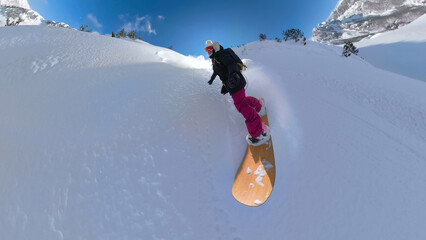 SELFIE Fearless female snowboarder enjoys riding deep powder snow on a sunny day