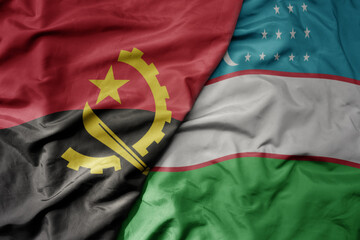 big waving national colorful flag of uzbekistan and national flag of angola .