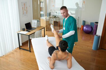 Physiotherapist examining female patient recovering from leg injury